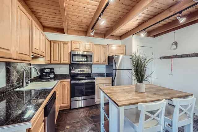 a kitchen with stainless steel appliances granite countertop a sink a stove and a wooden cabinets