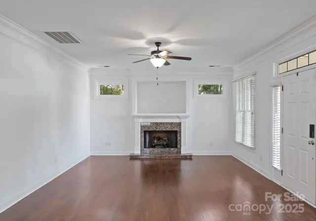 a view of a livingroom with a fireplace a ceiling fan and windows