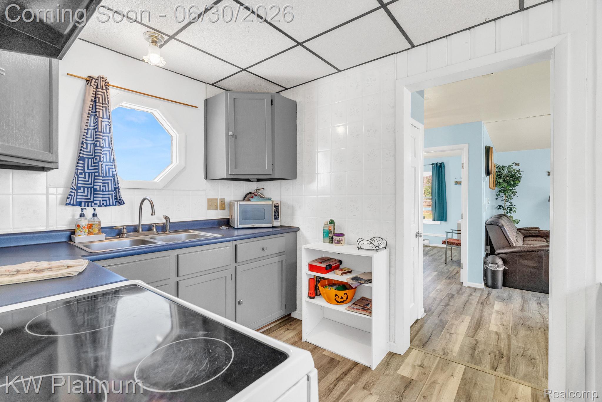 2235 South Lake Shore Road Harbor Beach, MI 48441 - Photo 63 of 99 Kitchen featuring grey cabinetry, blue countertops, a double basin sink with a gooseneck faucet, a white tile backsplash, and an octagonal window