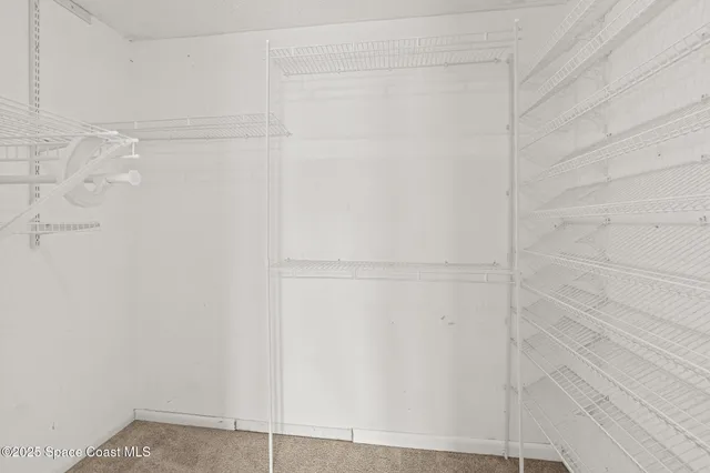 a view of hallway with closet and a chandelier fan