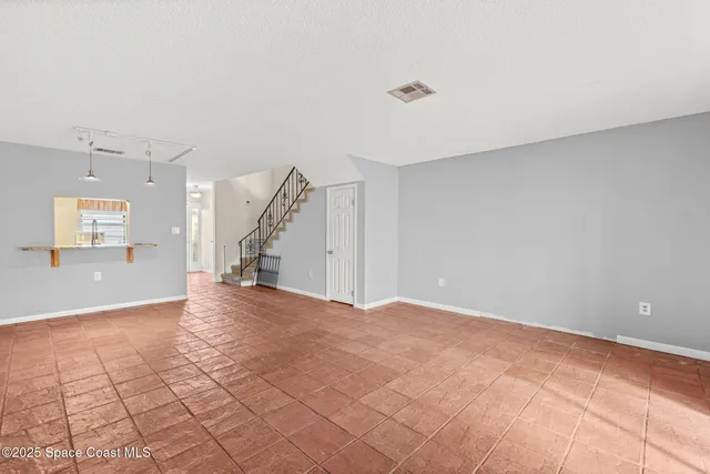 a view of an empty room with wooden floor and staircase