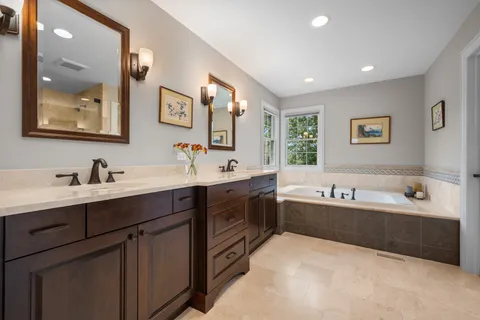 a spacious bathroom with a double vanity sink mirror and bathtub