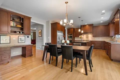 a kitchen with stainless steel appliances kitchen island granite countertop a table chairs and a wooden cabinets