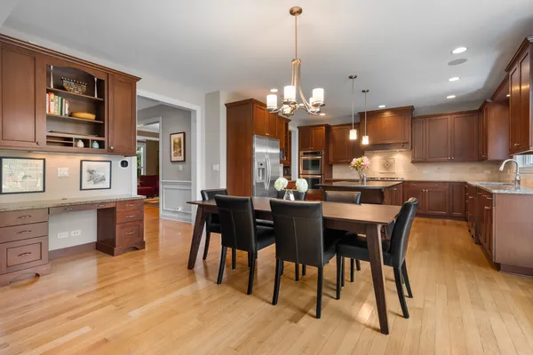 a kitchen with stainless steel appliances kitchen island granite countertop a table chairs and a wooden cabinets