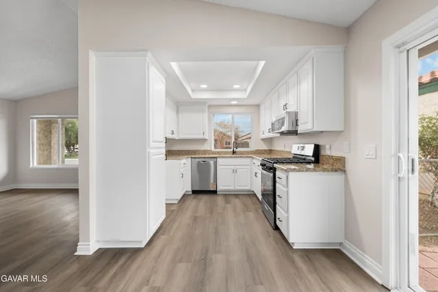 a kitchen with a white cabinets a sink a window and stainless steel appliances