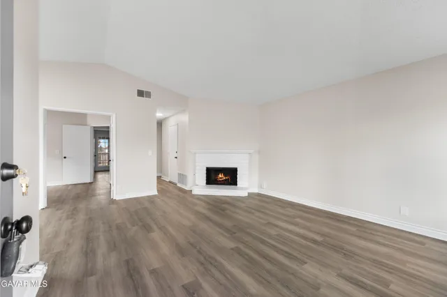 an empty room with wooden floor and fireplace