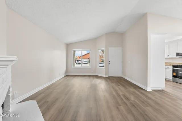 an empty room with wooden floor closet and windows