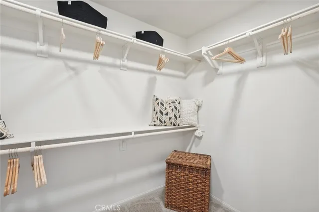 a view of walk in closet with clothes and shoes