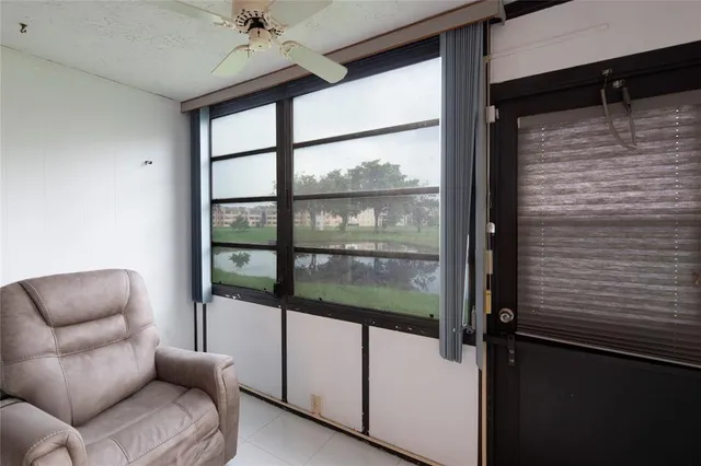a living room with furniture a floor to ceiling window and a ceiling fan