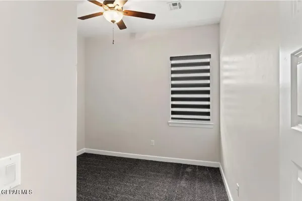 an empty room with a window and ceiling fan
