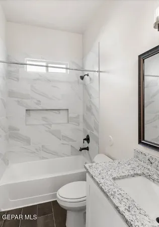 a bathroom with a granite countertop bathtub shower sink vanity and toilet