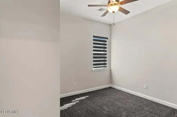 an empty room with a window and a fan