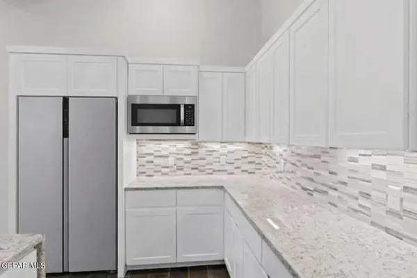 a kitchen with granite countertop white cabinets and stainless steel appliances