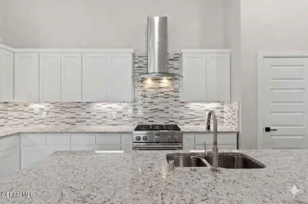 a kitchen with granite countertop a stove and white cabinets