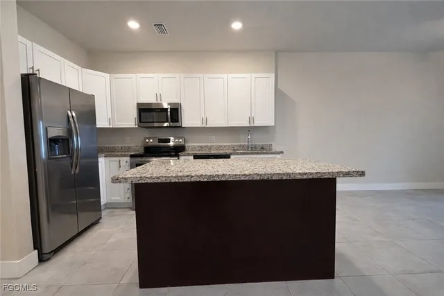 a kitchen with stainless steel appliances granite countertop a refrigerator a sink a stove a microwave and a refrigerator