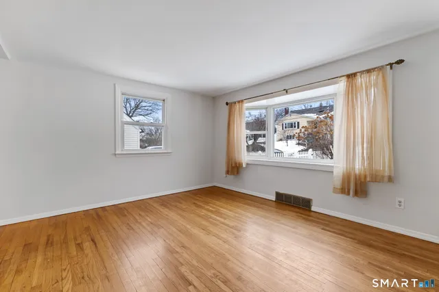 a view of empty room with window and wooden floor