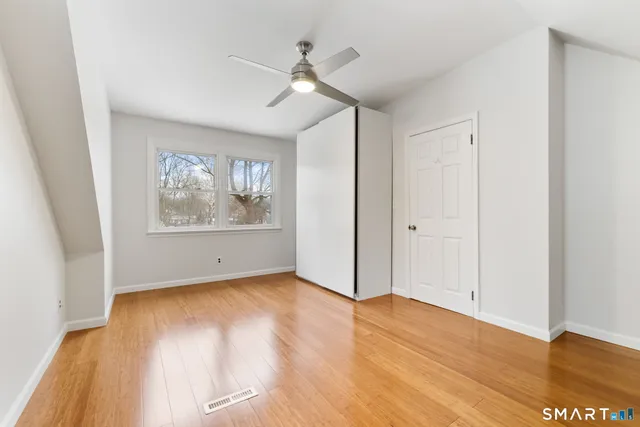 an empty room with wooden floor chandelier fan and windows