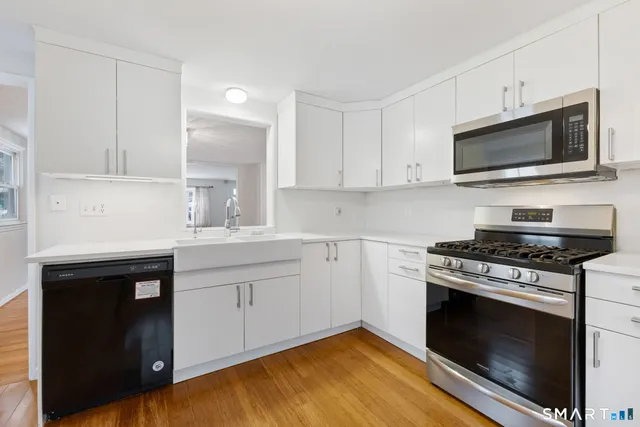 a kitchen with stainless steel appliances white cabinets and a stove top oven
