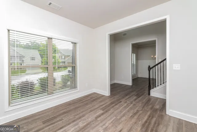 a view of an empty room with wooden floor and a window