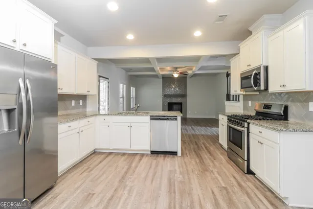 a large kitchen with stainless steel appliances kitchen island granite countertop a stove a sink dishwasher and a refrigerator with wooden floor