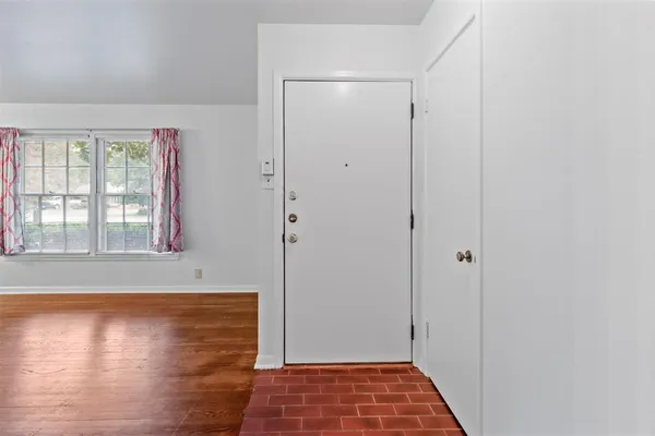 a view of an empty room with window and wooden floor
