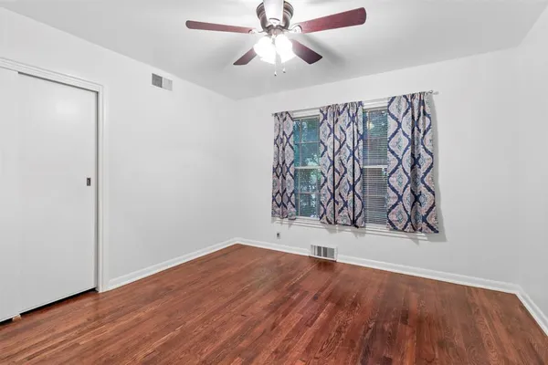 an empty room with wooden floor and a ceiling fan