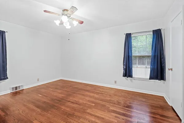 a view of an empty room with window and wooden floor