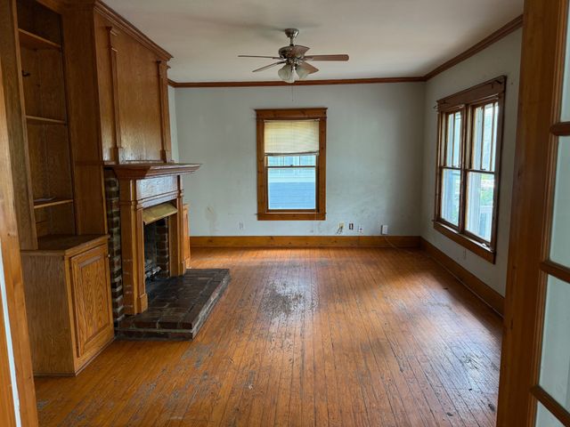 an empty room with wooden floor fireplace and windows