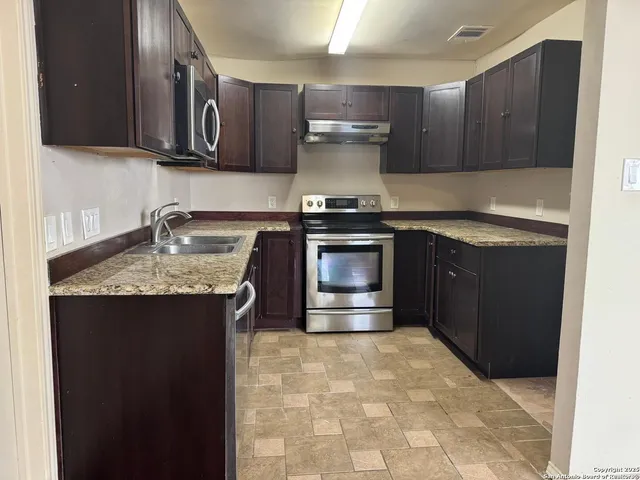a kitchen with stainless steel appliances granite countertop a stove a sink and a microwave