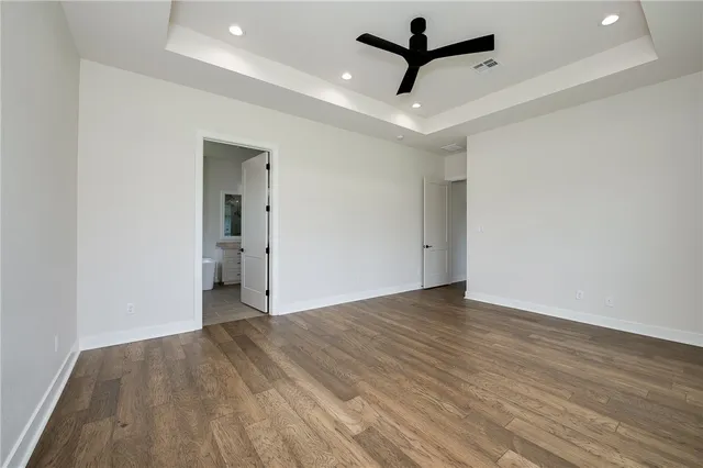 an empty room with wooden floor and ceiling fan