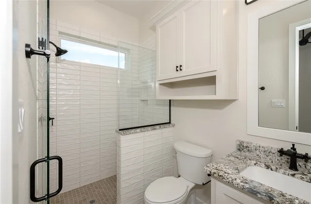 a bathroom with a granite countertop toilet sink and mirror