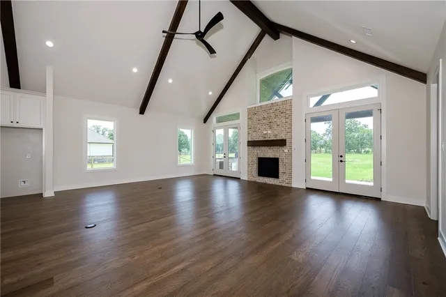 an empty room with wooden floor fireplace and windows