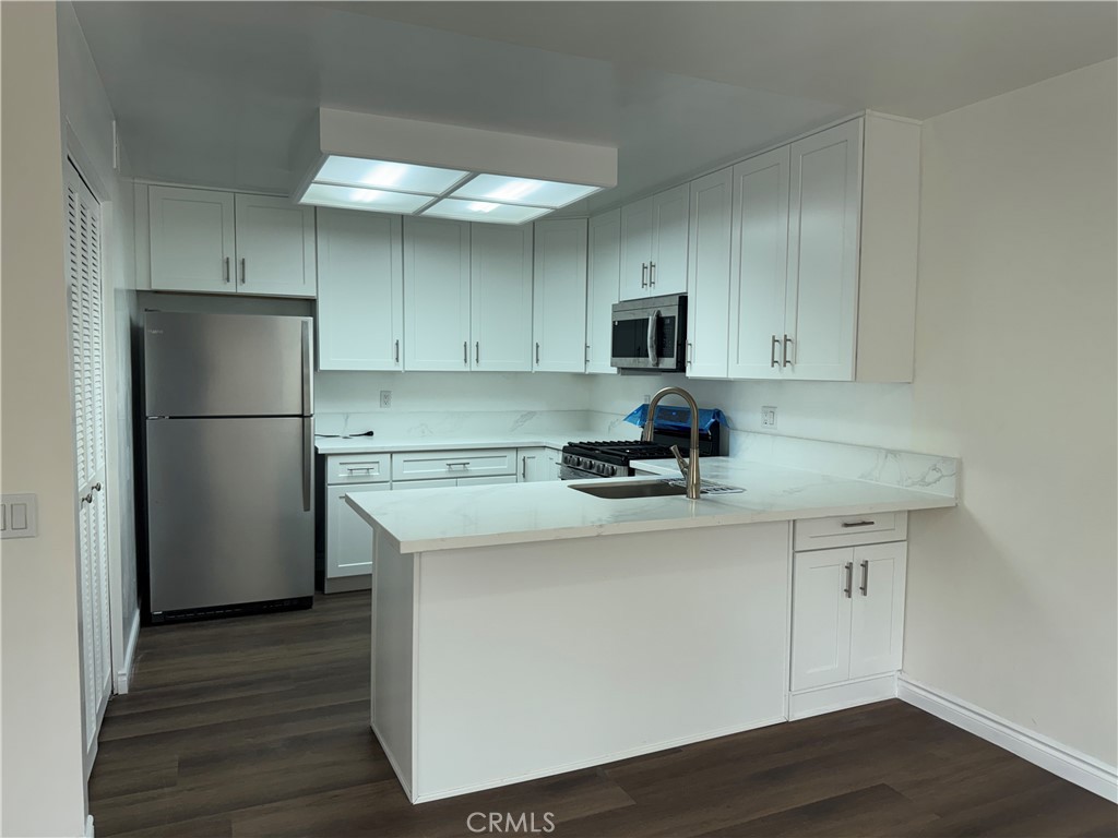 6 Columbia, Unit 2 Irvine, CA 92612 - Photo 14 of 25 a kitchen with stainless steel appliances granite countertop a refrigerator stove a sink and white cabinets with wooden floor