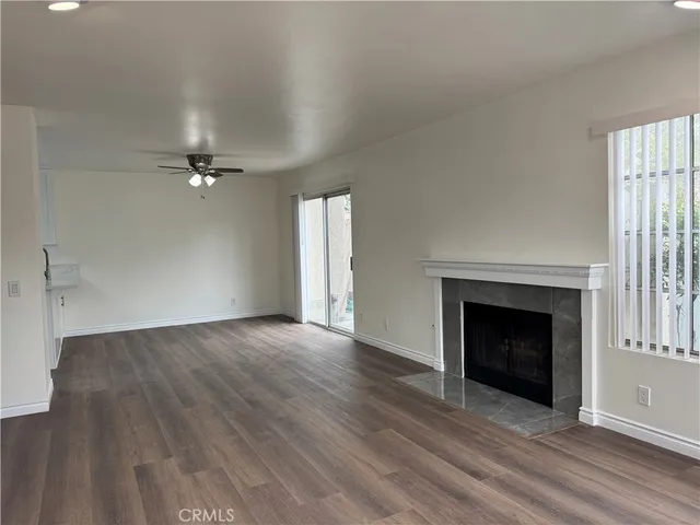 an empty room with wooden floor fireplace and windows