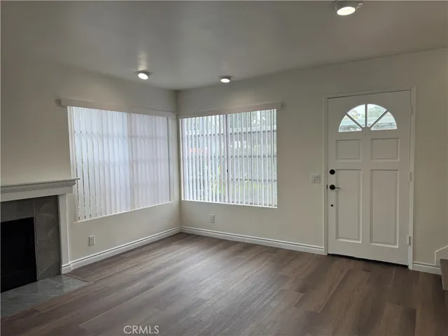 an empty room with wooden floor cabinet and windows