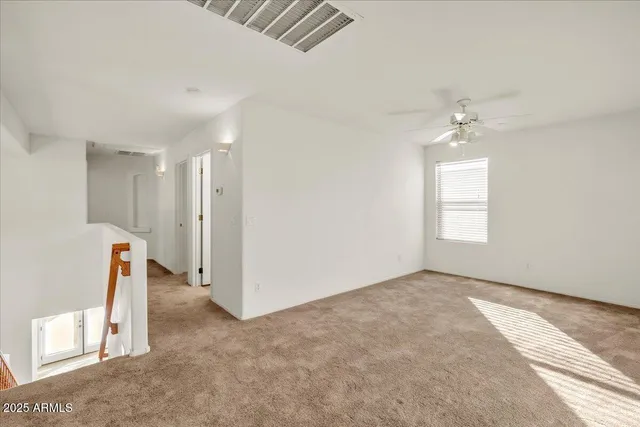 an empty room with a chandelier fan and windows