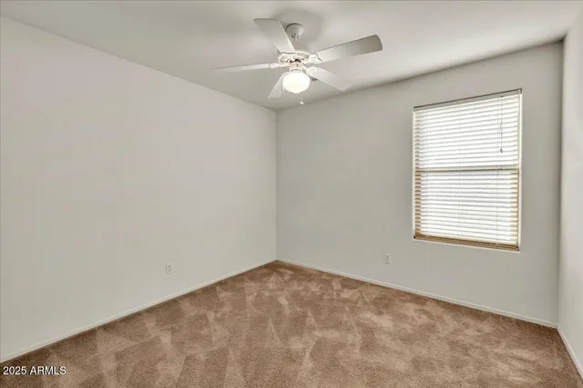 an empty room with a chandelier fan and windows