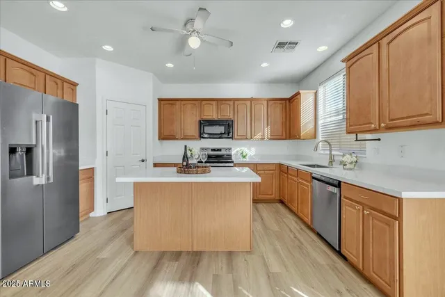 a large kitchen with stainless steel appliances granite countertop a stove a sink dishwasher and a refrigerator with wooden floor