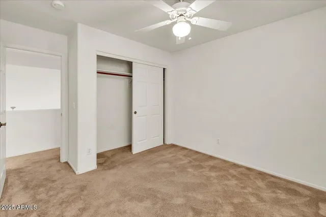 an empty room with a fan & a window