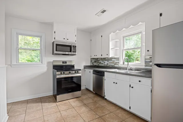 a kitchen with granite countertop white cabinets and appliances