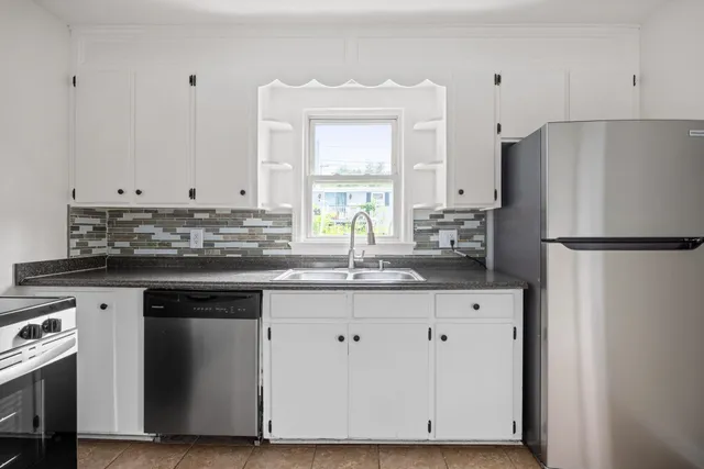 a kitchen with granite countertop white cabinets and refrigerator
