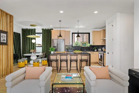 a living room with furniture a large window and kitchen view