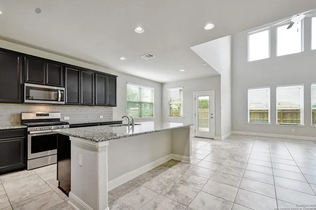 a large kitchen with stainless steel appliances granite countertop a stove a sink and a microwave