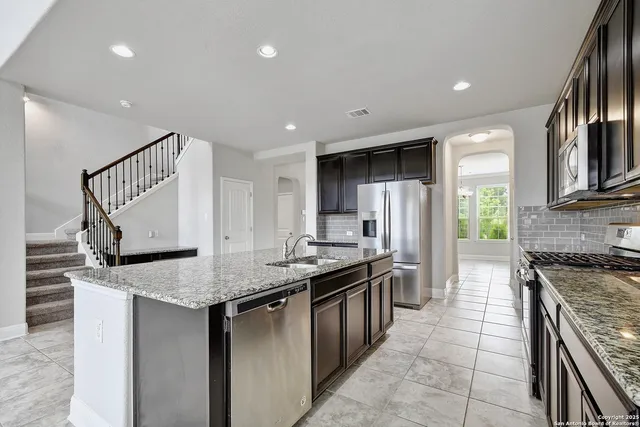 a kitchen with stainless steel appliances granite countertop a stove a sink and a refrigerator