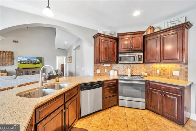 a kitchen with stainless steel appliances granite countertop a refrigerator and a stove top oven