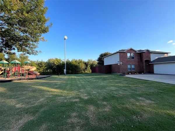 a view of a big house with a big yard and a large trees