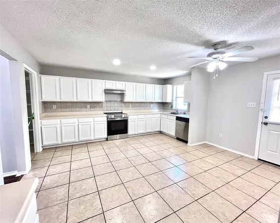 a kitchen with a stove a refrigerator and white cabinets