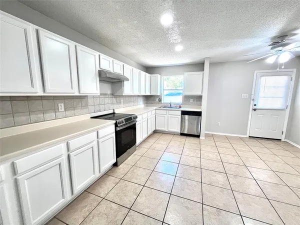 a kitchen with a cabinets a sink a window and stainless steel appliances