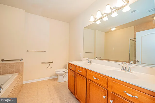 a spacious bathroom with a granite countertop sink a toilet and a bathtub