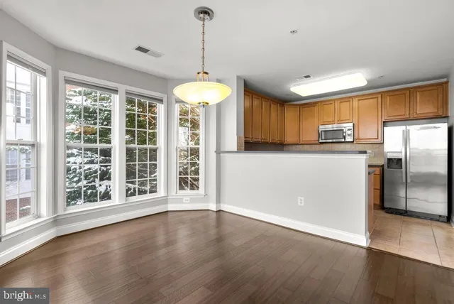 a view of a kitchen with a refrigerator a ceiling fan and a wooden floor